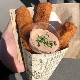 a person holding a container of fried food