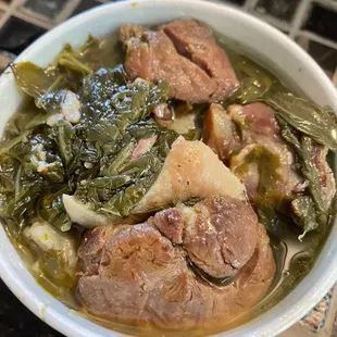 a bowl of soup with meat and greens