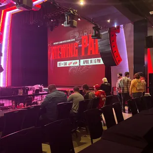 people sitting in chairs in front of a stage