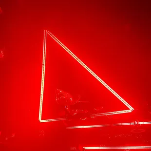 a triangle shaped neon sign on a stage