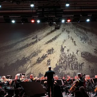 a conductor and orchestra performing on stage