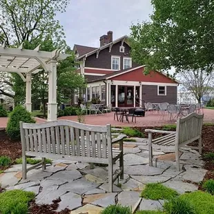 ows a stone patio with a bench and pergol