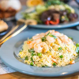 a plate of fried rice with shrimp and vegetables