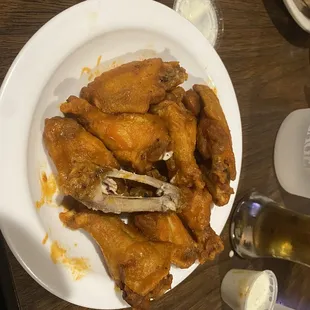a plate of chicken wings and a bottle of beer