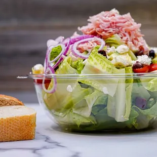 a salad in a bowl with a side of bread