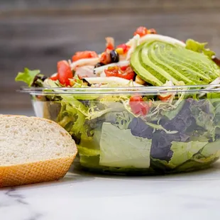 a salad in a bowl with a side of bread