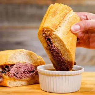 a person dipping a sandwich into a bowl