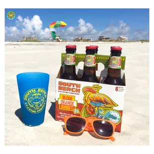 a bottle of beer and sunglasses on the beach