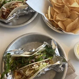 two plates of tacos and chips