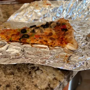 ows a slice of pizza on aluminum foil