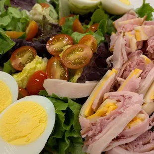 a salad with ham, tomatoes, and hard boiled eggs
