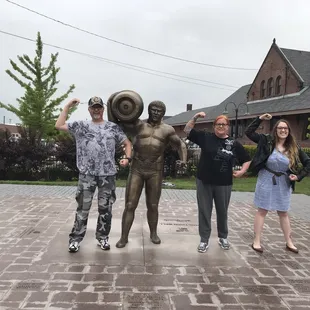 a group of people posing in front of a statue