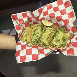 a person holding a basket of tacos