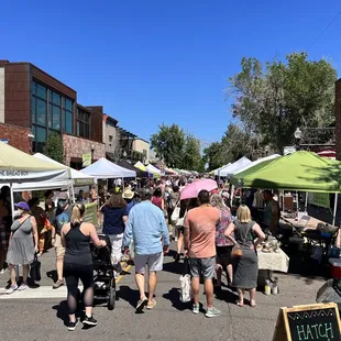 a crowd of people shopping at an outdoor market