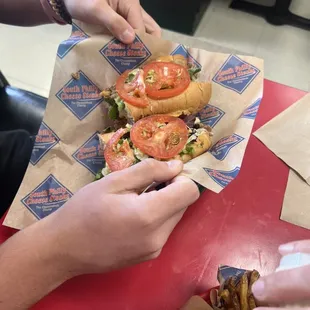 two hands grabbing a sandwich