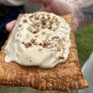 a hand holding a cracker with cream cheese on it