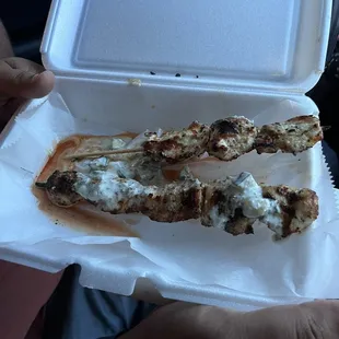 a person holding a piece of food in a styrofoam container