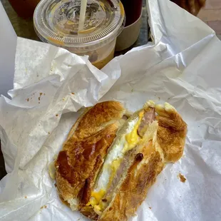 croissant breakfast sandwich with egg and sausage. Vietnamese iced coffee