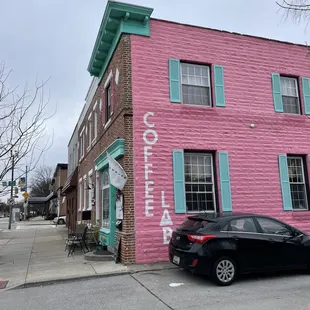 a car parked in front of a pink building