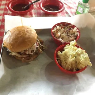 Pulled pork sandwich, coleslaw, potato salad. Two different types of barbecue sauce