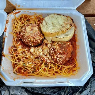 a takeout box of spaghetti and meatballs