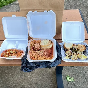 three take out boxes of food on a picnic table