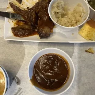 a plate of ribs, mashed potatoes, and gravy