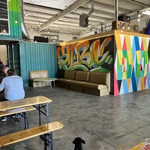 people sitting at tables in front of a colorful mural