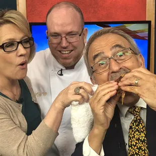 a man eating a sandwich with two women