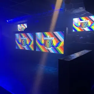 a brightly lit stage with three televisions