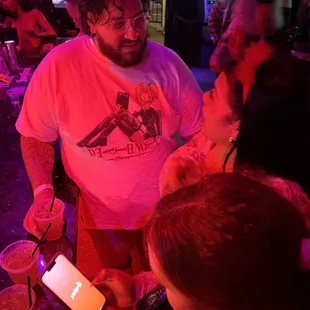 a man in a white t - shirt and red shorts standing in front of a crowd of people