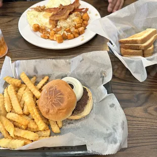 Breakfast plate with eggs, bacon, home fries.  Hamburger with fries.