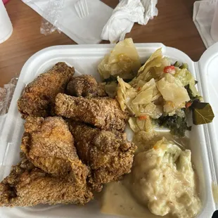 a tray of fried chicken, mashed potatoes, cabbage, and gravy