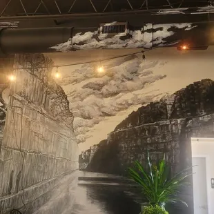 Really beautiful landscape artwork that shows two people standing alongside a river.