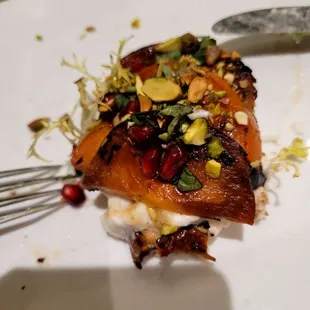 Closeup of a half eaten, grilled persimmon and burrata cheese crostini.