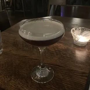 a cocktail in a coupe glass on a wooden table