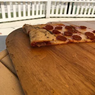 a slice of pepperoni pizza on a cutting board