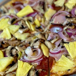 a pizza with pineapples, mushrooms, and onions