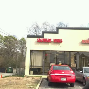 a red car parked in front of a restaurant