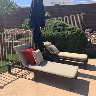 two lounge chairs and an umbrella