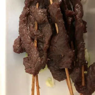 beef skewered on skewers on a white plate