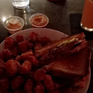 Cuban pulled mojo pork grilled sandwich with ham, mustard, pickles, swiss on toasted sourdough bread and tater tots.