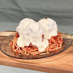 a plate of spaghetti topped with mozzarella