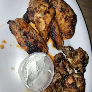 a plate of grilled chicken wings with ranch dressing