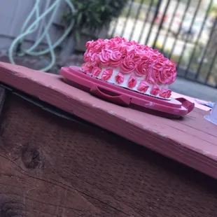 a pink and white cake on a wooden table