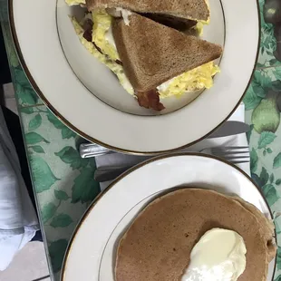 Bacon egg and cheese sandwich on wheat and a side of pancakes.