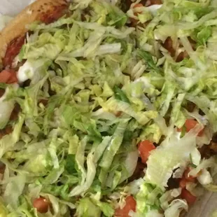 a pizza topped with lettuce and tomatoes