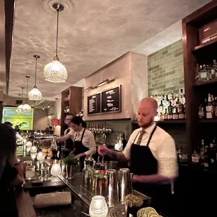 a bartender at a bar with a bartender in the background