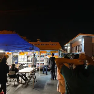 a group of people standing under a blue tent