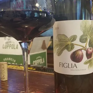 a glass of red wine and a bottle of figlia